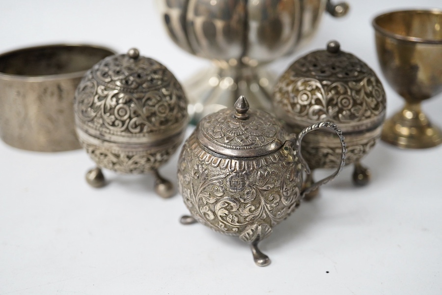 An Indian white metal three piece condiment set, a continental white metal jug, height 14cm, a silver egg cup and an engraved white metal hinged bangle. Condition - poor to fair